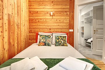 A bedroom with a wooden wall and a bed