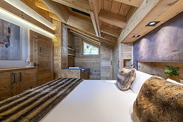 A bedroom with a wooden ceiling and a bed