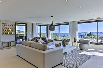 A living room with a couch and chairs with a view of the ocean