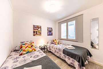 A bedroom with two beds and two paintings on the wall