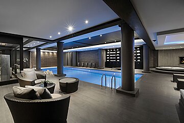 A large indoor swimming pool surrounded by chairs and tables