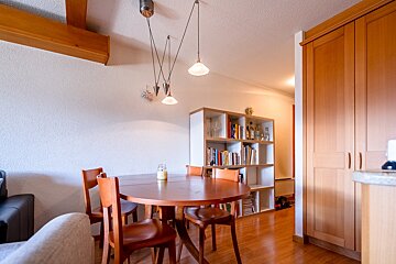 A dining room with a table and chairs and a bookshelf
