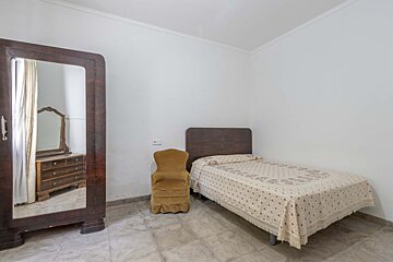 A bedroom with a single bed and a chair