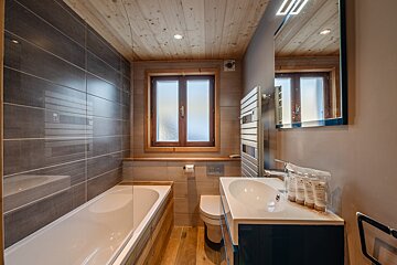 A bathroom with a sink toilet and window