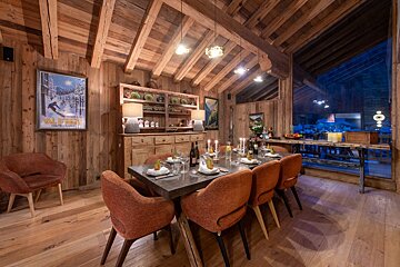 A wooden dining room with a poster on the wall that says alpin