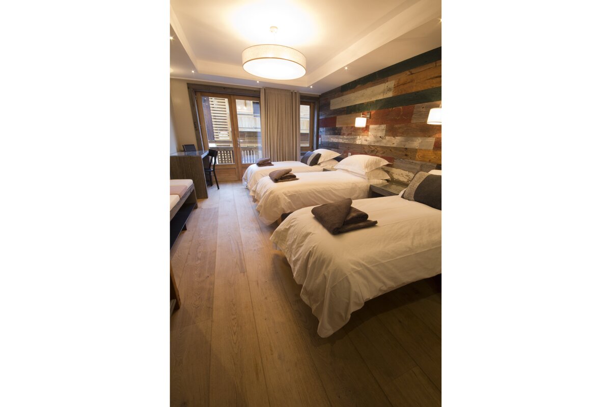 A hotel room with three beds and a window