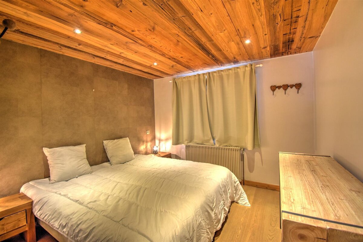 A bedroom with a wooden ceiling and a bed