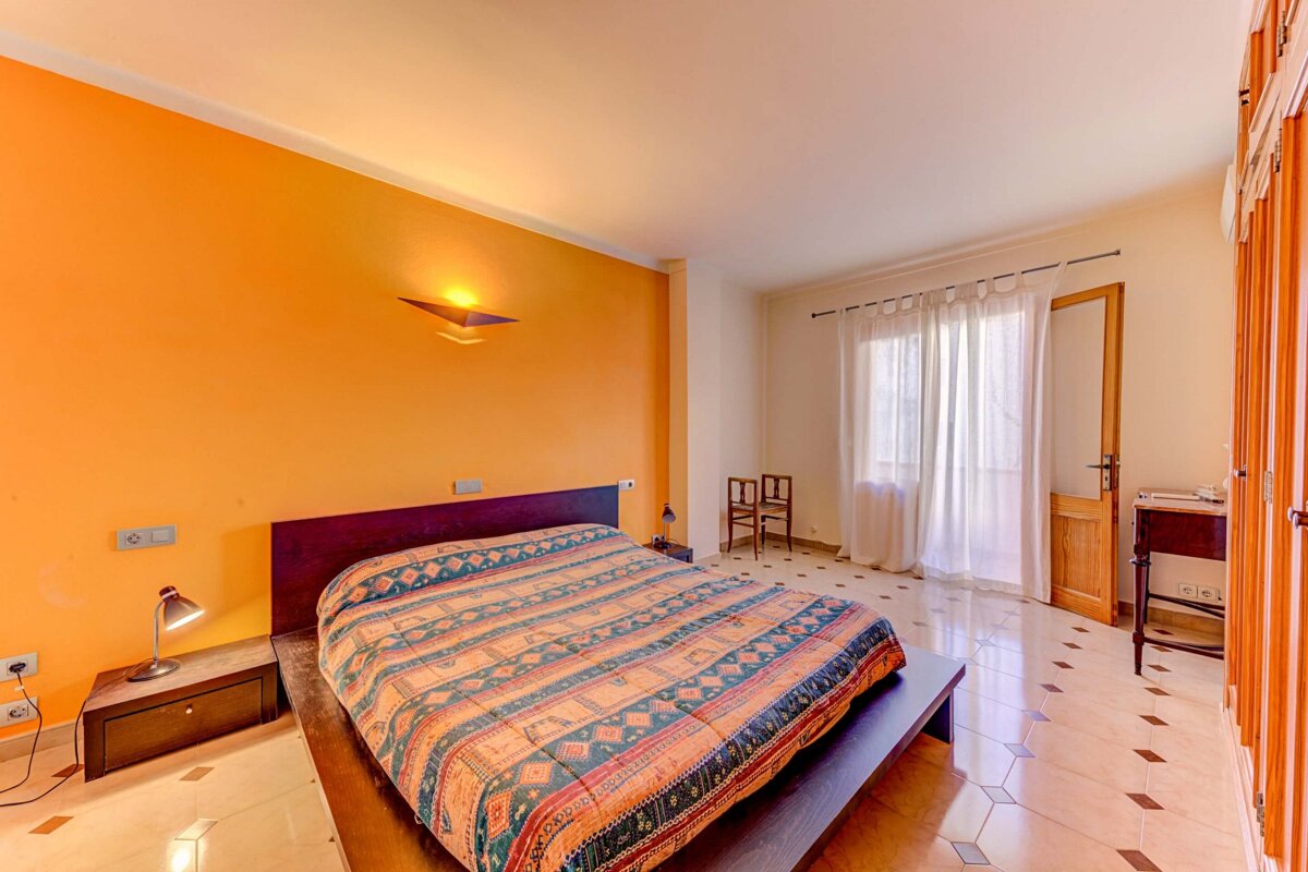 A bedroom with an orange wall and a bed