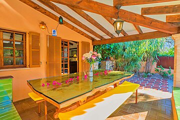 A glass table with flowers on it sits on a patio