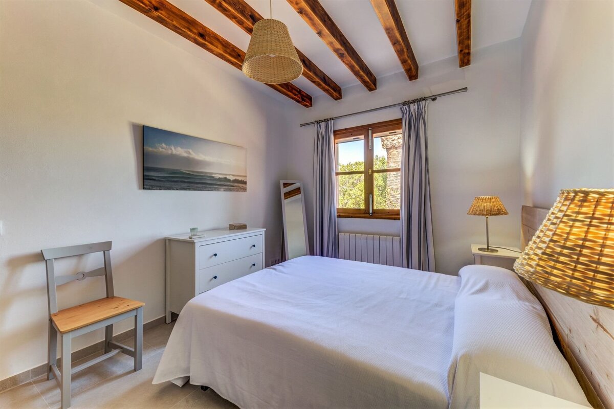A bedroom with a painting on the wall above the bed