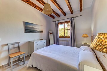 A bedroom with a painting on the wall above the bed