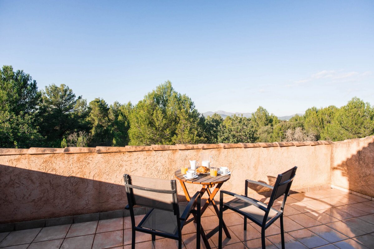 A balcony with a table and chairs with a view of trees