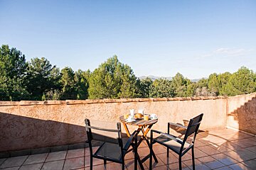 A balcony with a table and chairs with a view of trees