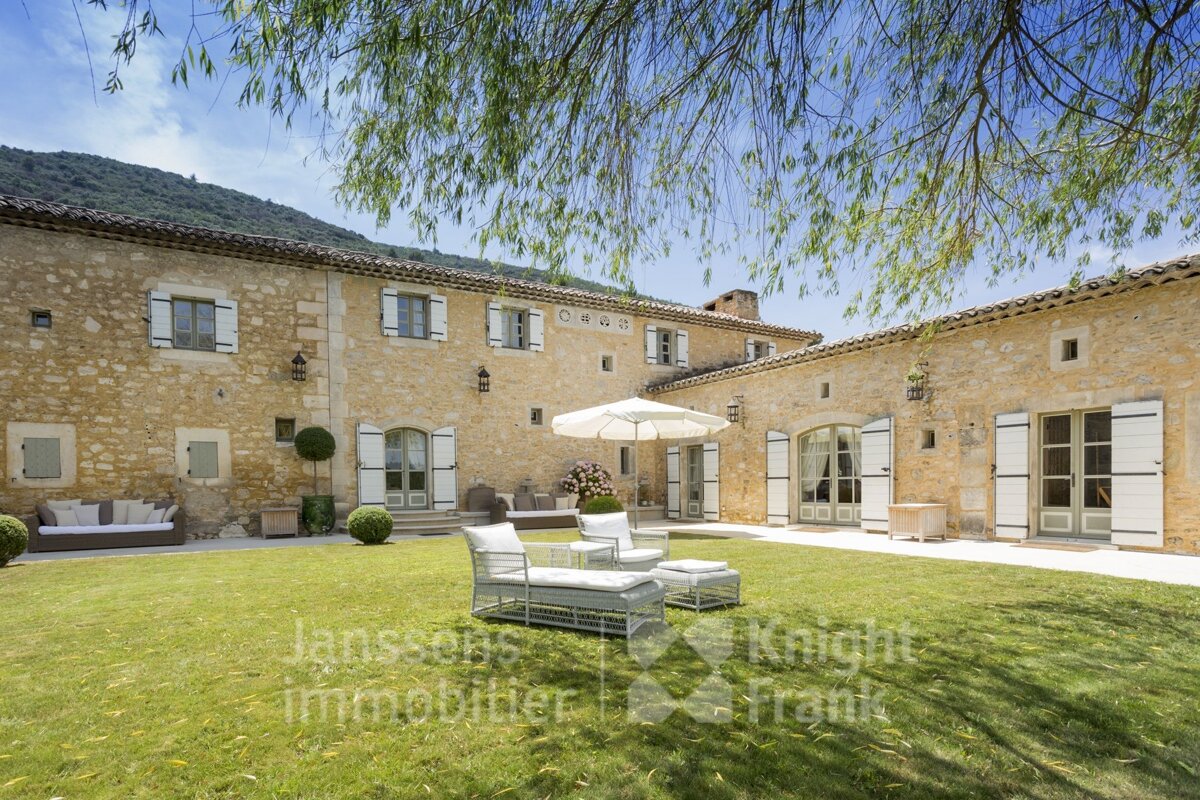 A large stone building with white shutters is for sale by jansson immobilier