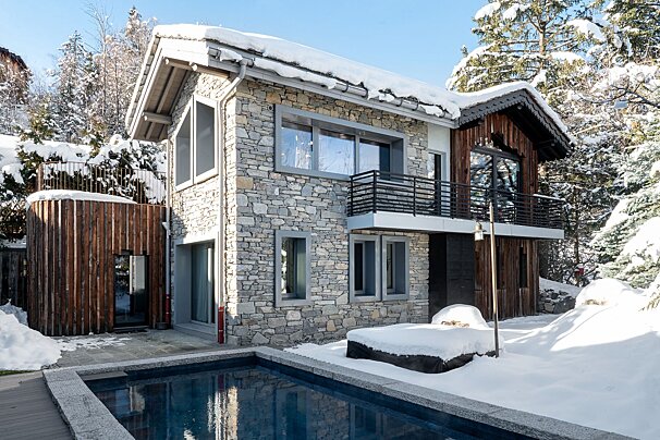 A stone house with a swimming pool in front of it