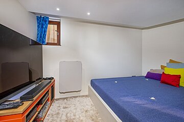 A bedroom with a blue bed and a flat screen tv