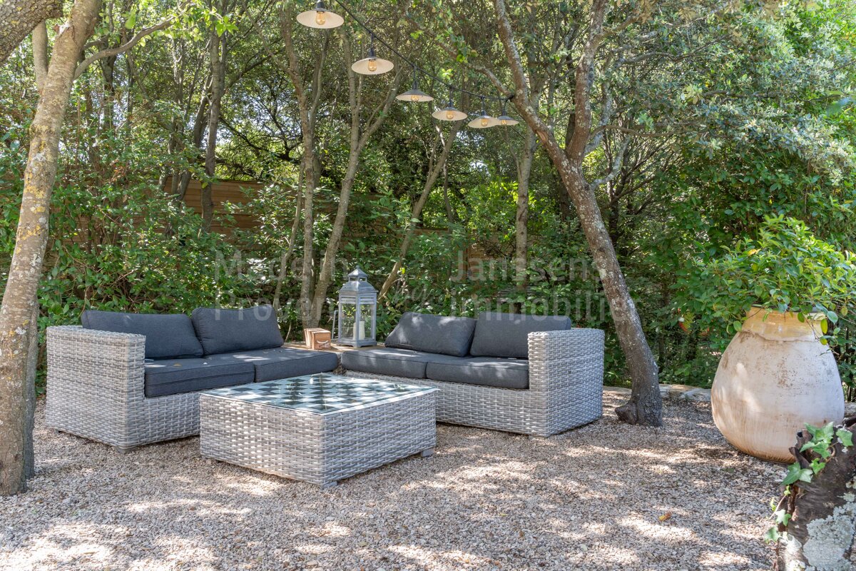 A patio area with a couch and a table with a lantern hanging from a tree