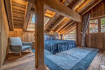 A bedroom with a large bed and a chair