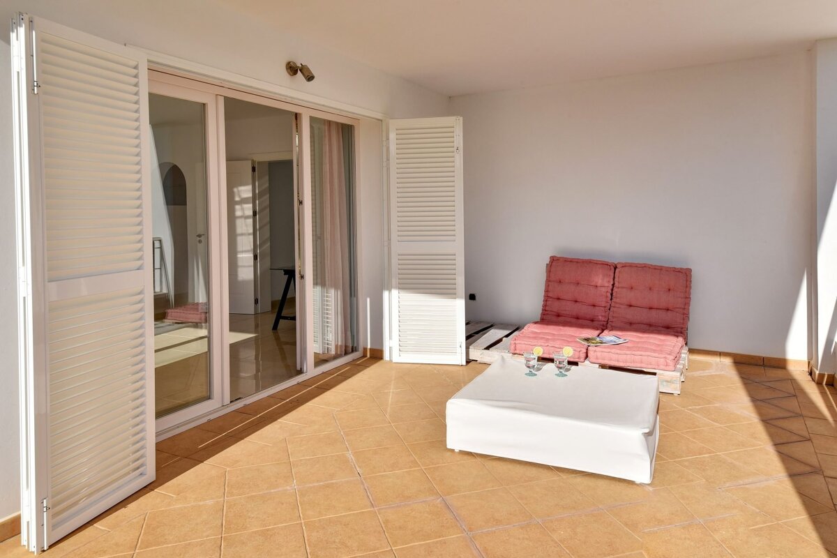 A patio with a white table and a pink chair