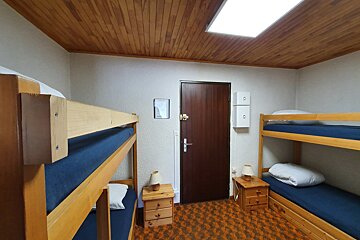 A room with bunk beds and nightstands and a door