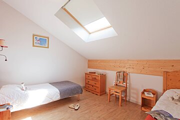 A bedroom with two beds a dresser and a skylight