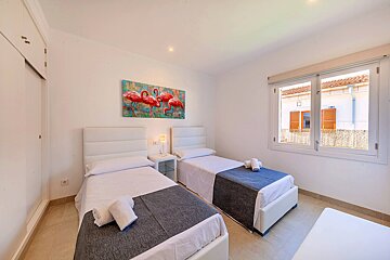 A bedroom with two beds and a painting of flamingos on the wall