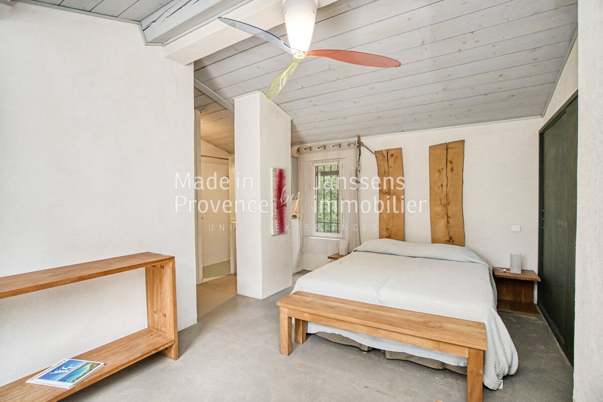 A bedroom with a bed and a ceiling fan made by janssens provence immobilier