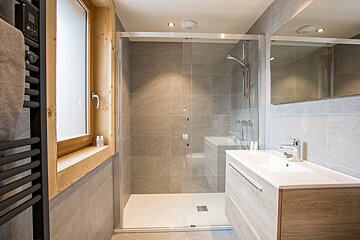 A bathroom with a walk in shower and a sink