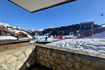 A view of a ski slope from a balcony with a ski lift in the background