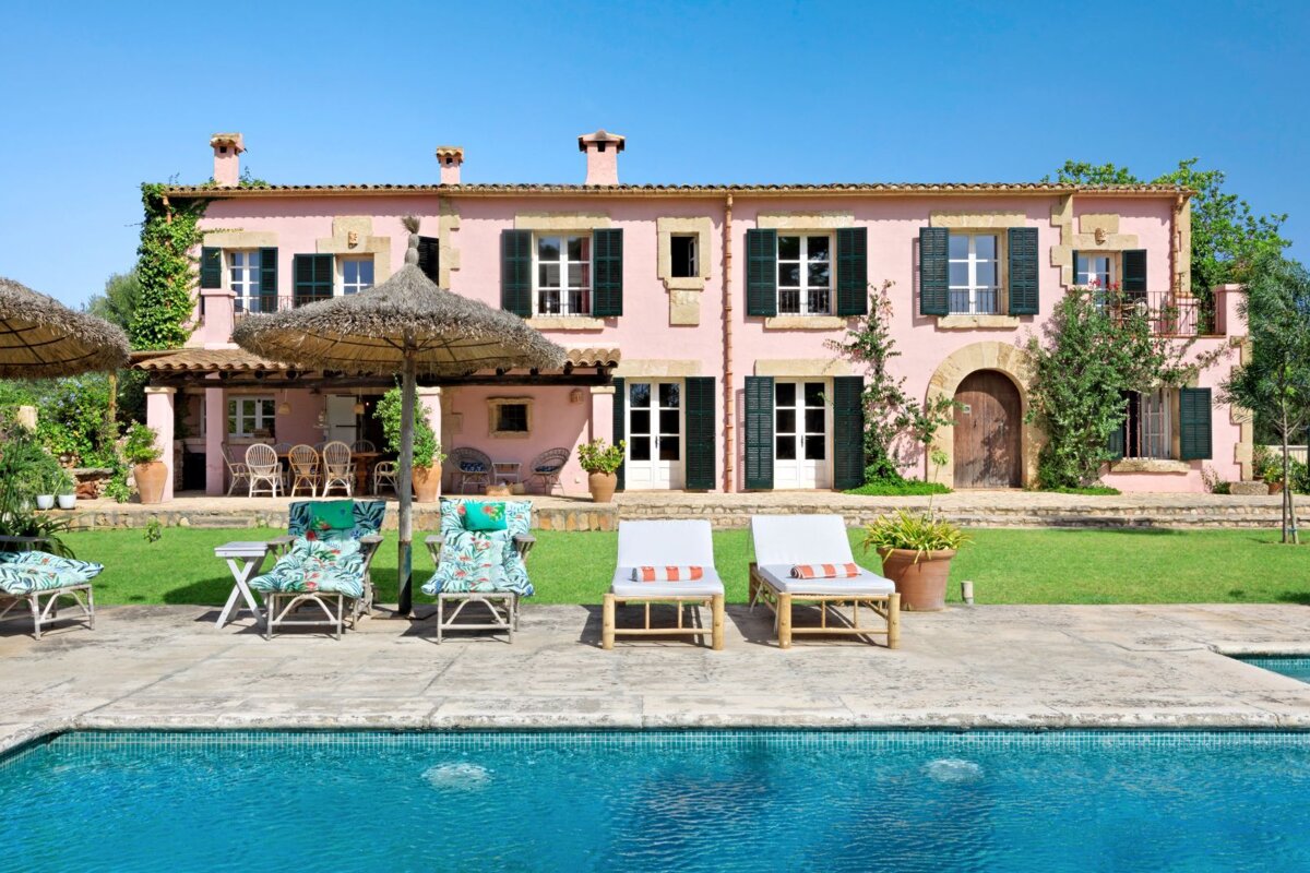 A large pink house with a swimming pool in front of it