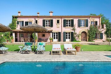 A large pink house with a swimming pool in front of it