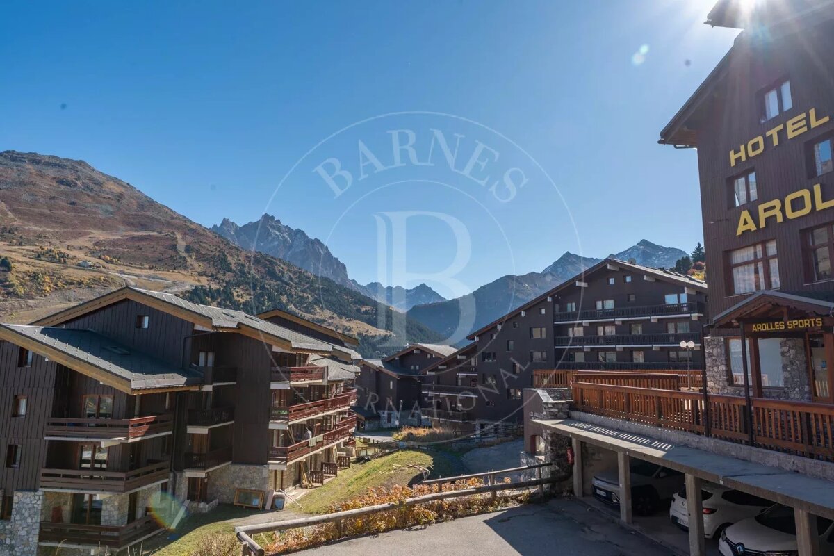 A sunny mountain village features chalet-style buildings with balconies and 