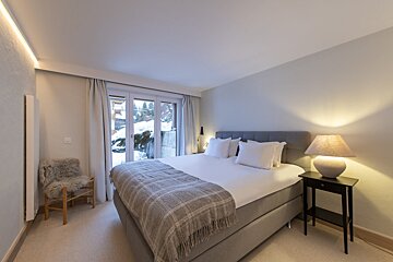 A bedroom with a large bed and two lamps