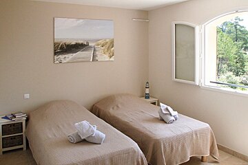 A bedroom with two beds and a painting on the wall