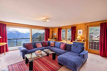 A living room with a blue couch and a glass coffee table