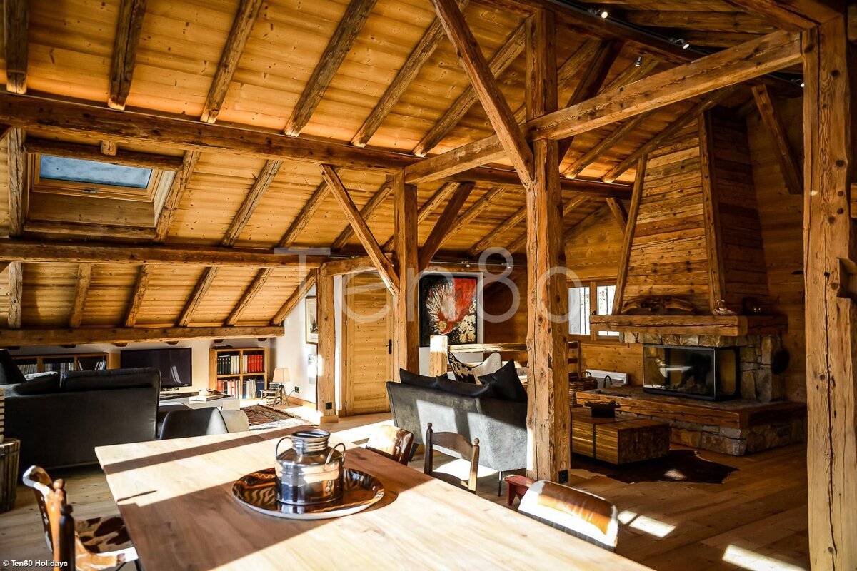 A living room with a wooden table and chairs and a fireplace