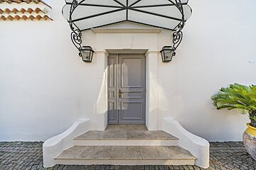 A white building with a gray door and steps