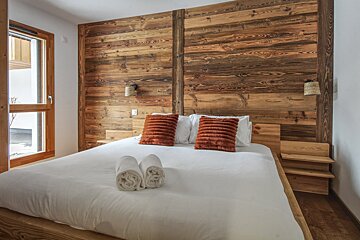 A bedroom with a wooden wall and a bed