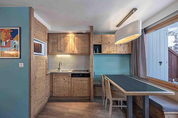 A kitchen with wooden cabinets and a table and chairs