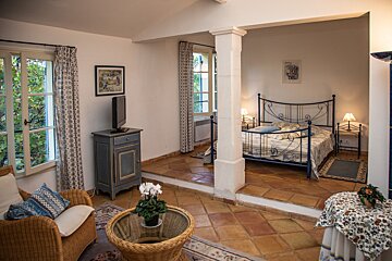 A bedroom with a wicker chair and a television
