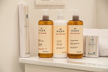 Three bottles of nuxe creme de miel are on a bathroom counter