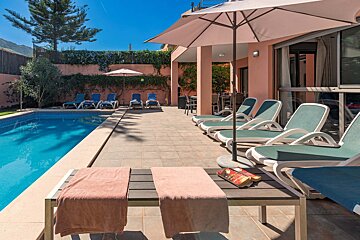 A swimming pool surrounded by lounge chairs and umbrellas