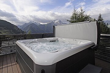 A hot tub on a deck with mountains in the background