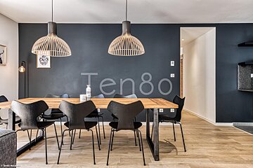 A dining room with a table and chairs and a wall that says ten80