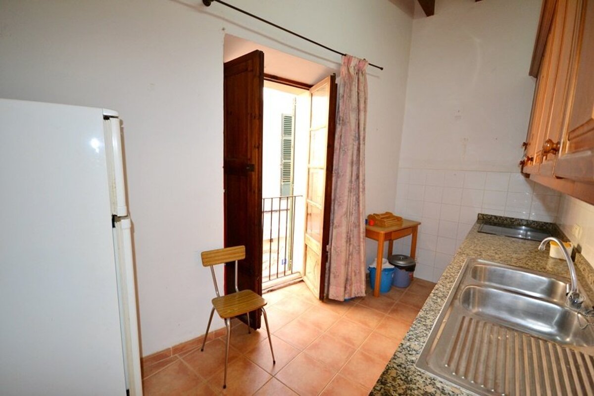 A kitchen with a white refrigerator and a wooden chair