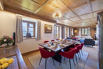 A dining room with a large table and red chairs
