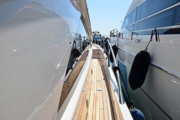 A boat with a wooden deck is docked next to another boat