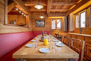 A wooden table with plates glasses and a bottle of orange juice on it