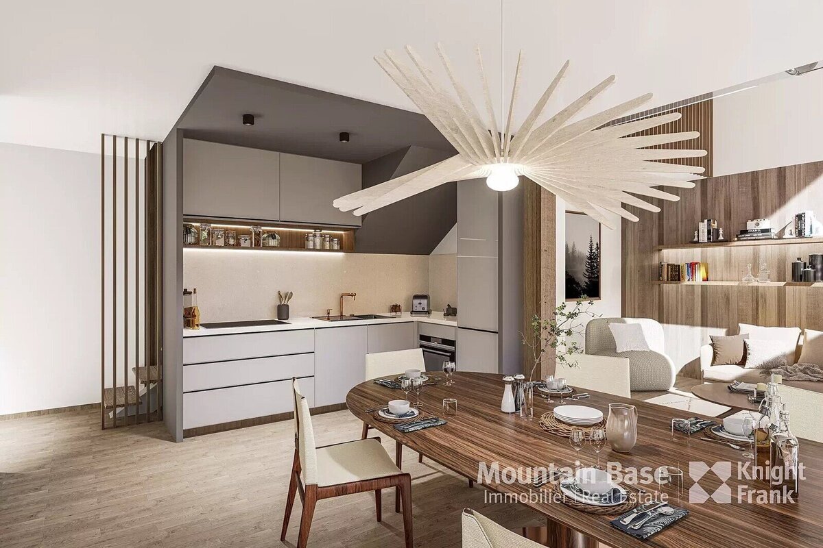 A modern open-plan space featuring a sleek kitchen, a wooden dining table set for guests, and a cozy living area with light sofas, all under a unique chandelier.