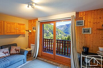 A living room with a couch and a balcony with mountains in the background